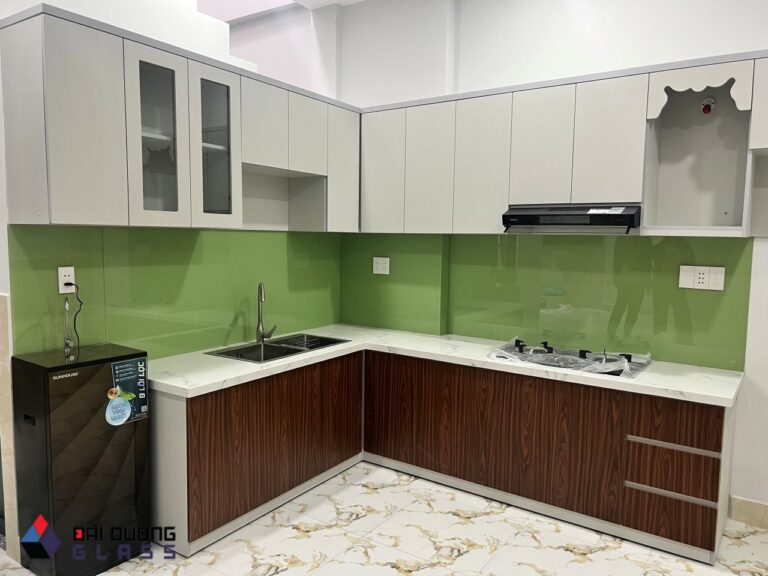 Bếp chữ L, kính ốp bếp xanh cốm, tủ trên trắng, tủ dưới vân gỗ